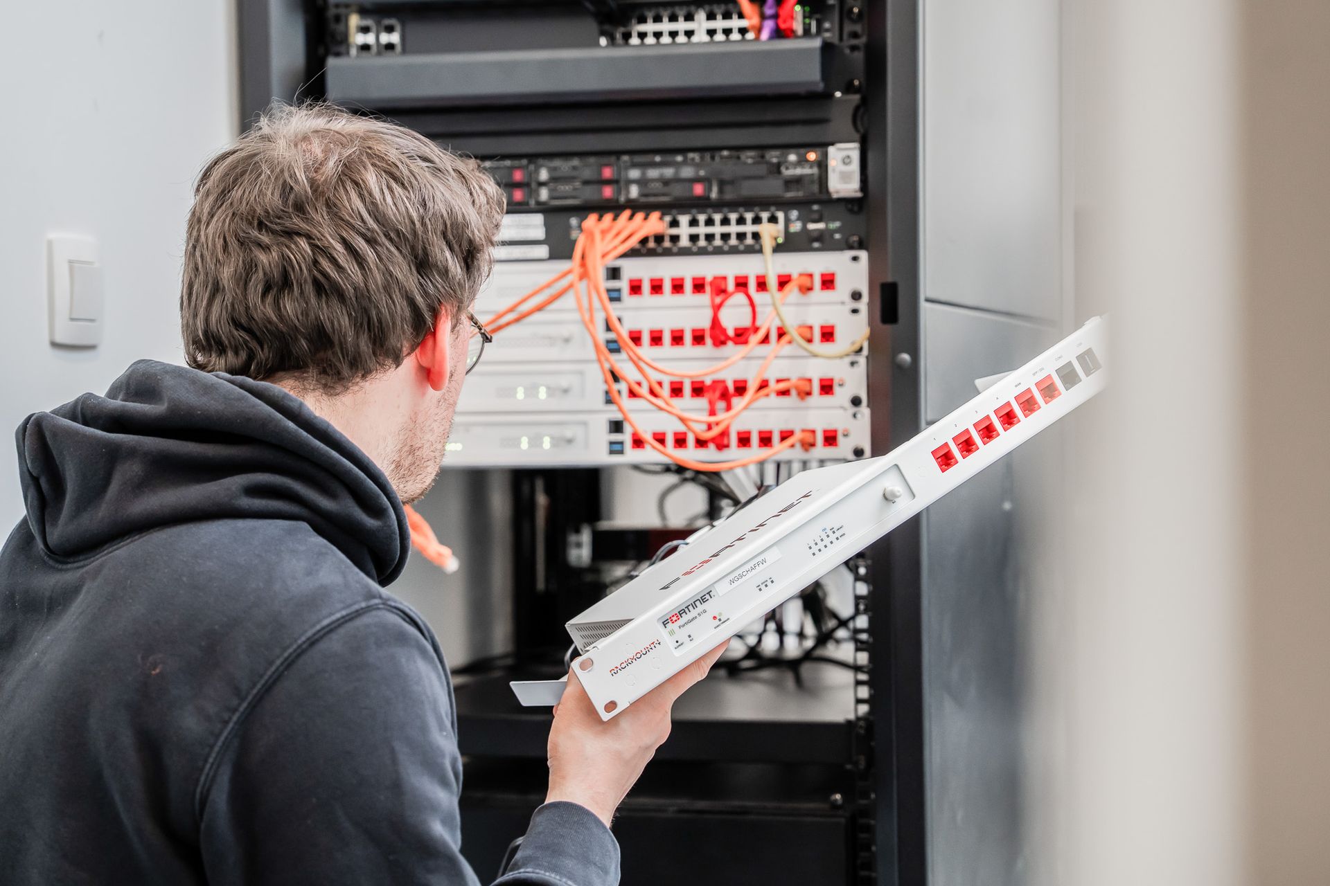 iemand die een firewall in de serverrack plaatst