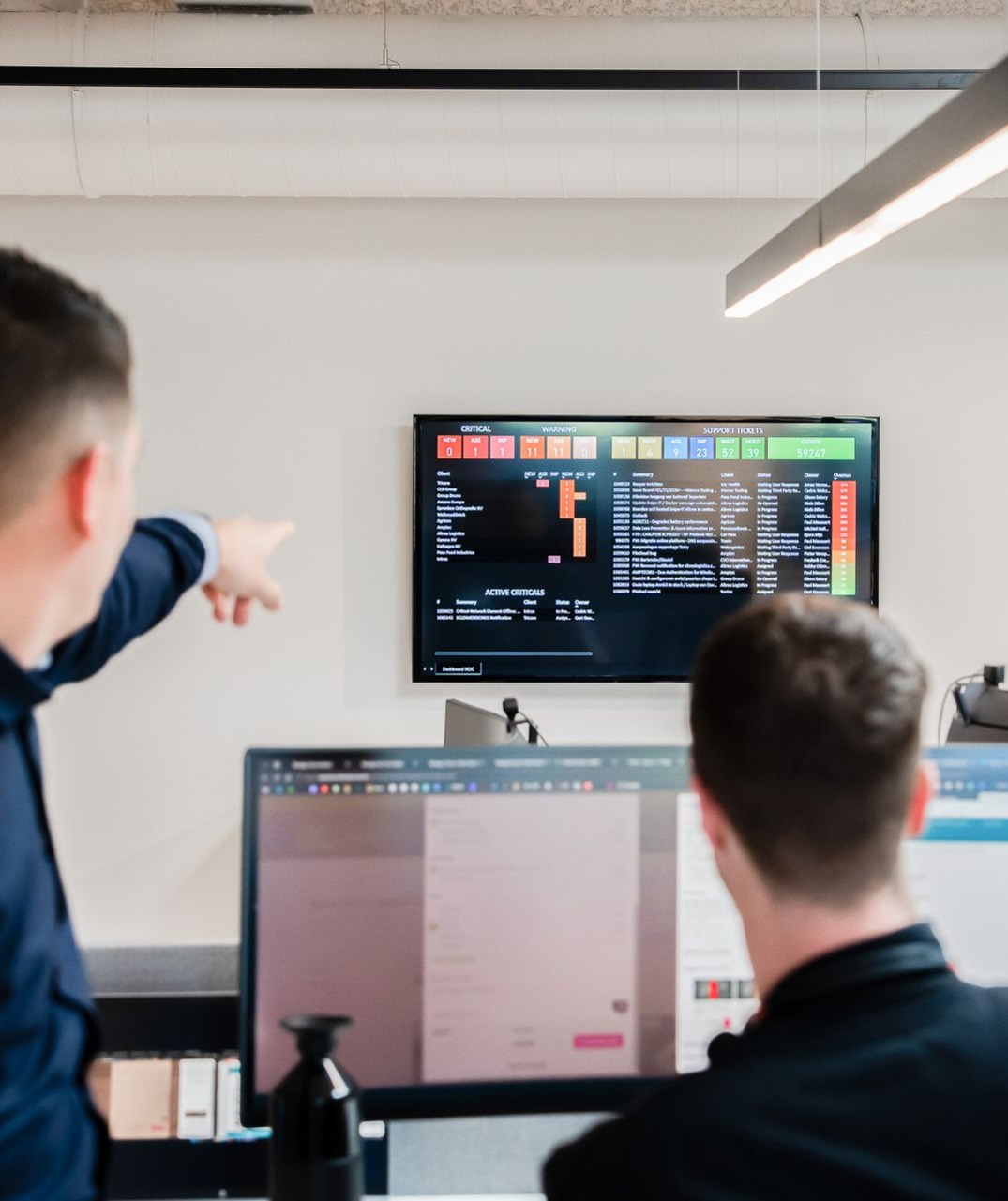 Twee collega's die iets bekijken op een NOC scherm